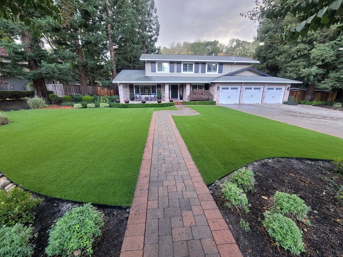 Large front yard artificial turf installation with brick walkway